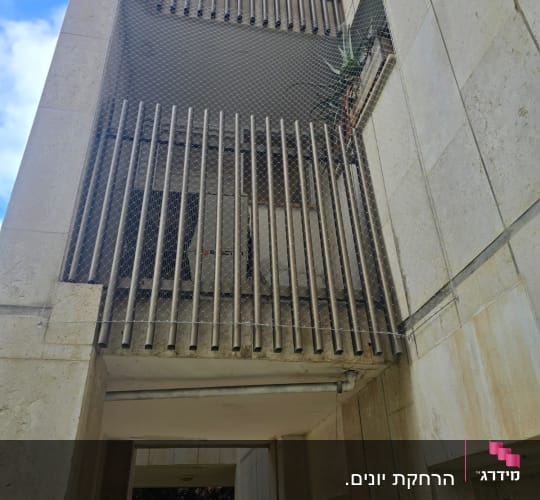 רשת מתכת מותקנת למניעת כניסת יונים במרפסת בניין